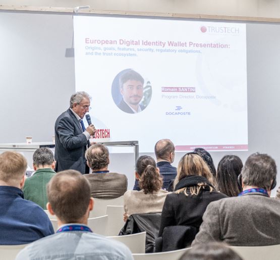 Conférencier introduisant la présentation "Portefeuille européen d’identité numérique" de Romain SANTINI lors du salon TRUSTECH 2024 devant un public attentif.