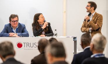 3 speakers on stage talking about instant payment in front of attendees in the TRUSTECH conference room