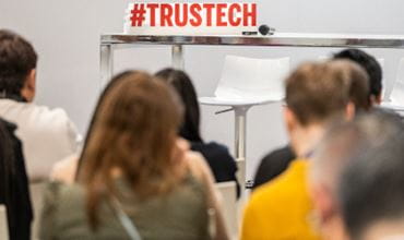 Audience view of an empty stage with the hashtag #TRUSTECH in the background, awaiting the start of the conference programme.