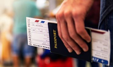 Gros plan d’une main tenant un passeport et une carte d’embarquement, symbolisant les risques liés à l’usurpation d’identité en période de vacances.