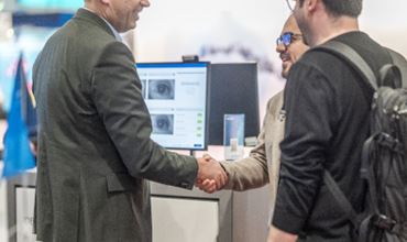 Poignée de main entre deux professionnels sur un stand dédié à l’identification biométrique lors du salon TRUSTECH.