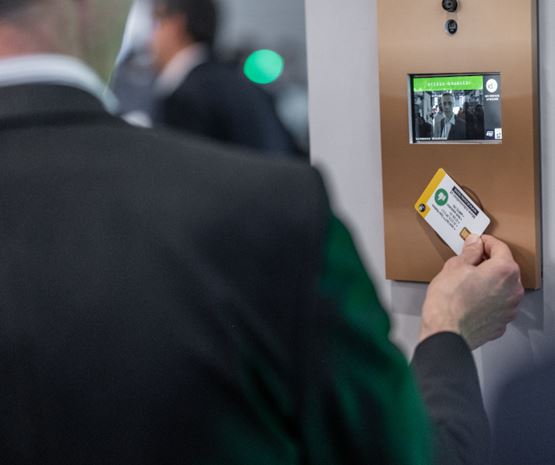 Démonstration d’un système de contrôle d’accès sécurisé par badge à TRUSTECH, où un homme pose un badge sur un lecteur avec caméra