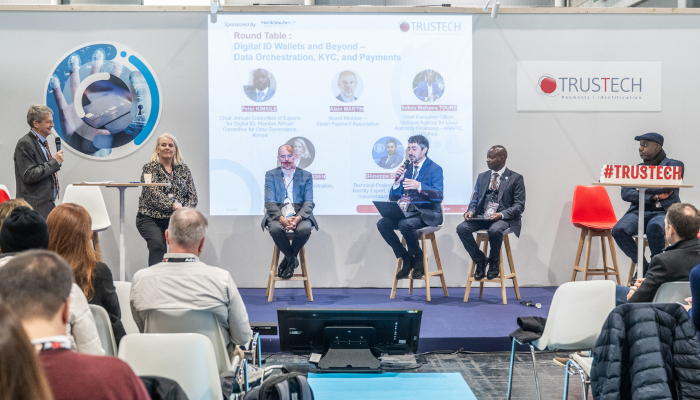 Table ronde à TRUSTECH 2025 avec des intervenants discutant sur scène des portefeuilles d'identité numérique et de l'orchestration des données, de la KYC et des paiements, devant plusieurs visiteurs