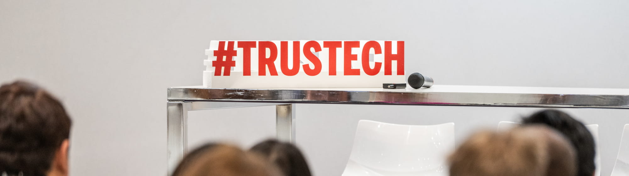 Audience view of an empty stage with the hashtag #TRUSTECH in the background, awaiting the start of the conference programme.