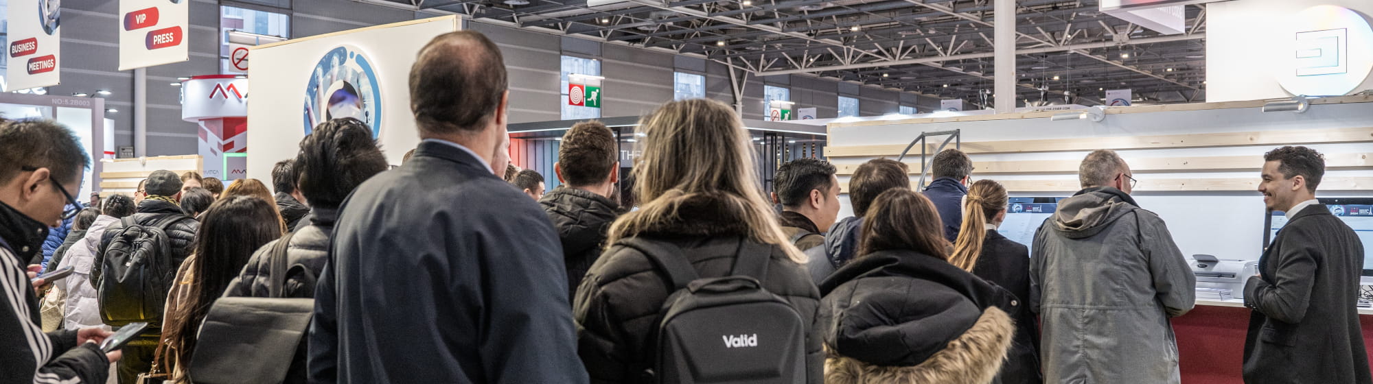 Crowd of visitors queuing at the entrance of a trade show in separated lines