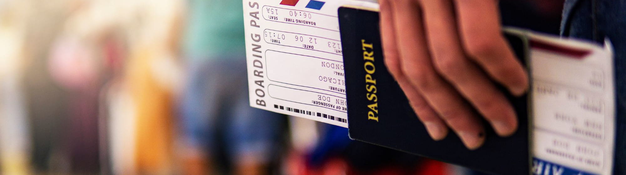 Gros plan d’une main tenant un passeport et une carte d’embarquement, symbolisant les risques liés à l’usurpation d’identité en période de vacances.