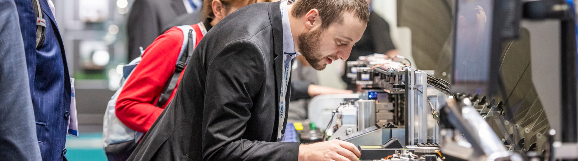 An exhibitor demonstrates a product to a visitor on his booth