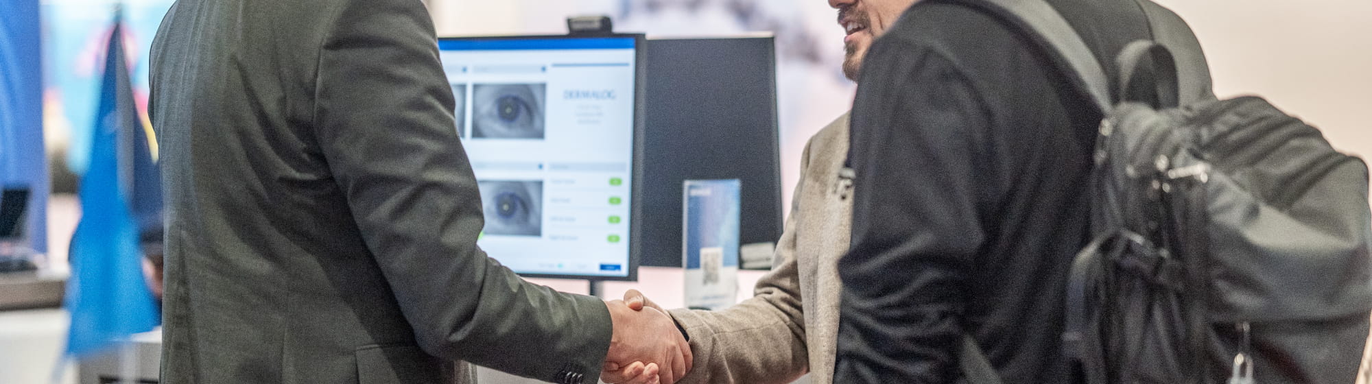 Poignée de main entre deux professionnels sur un stand dédié à l’identification biométrique lors du salon TRUSTECH.