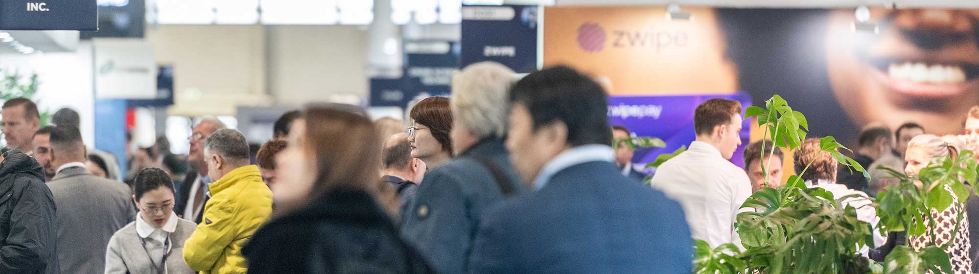 Visitors walking through Trustech aisle looking at the booths