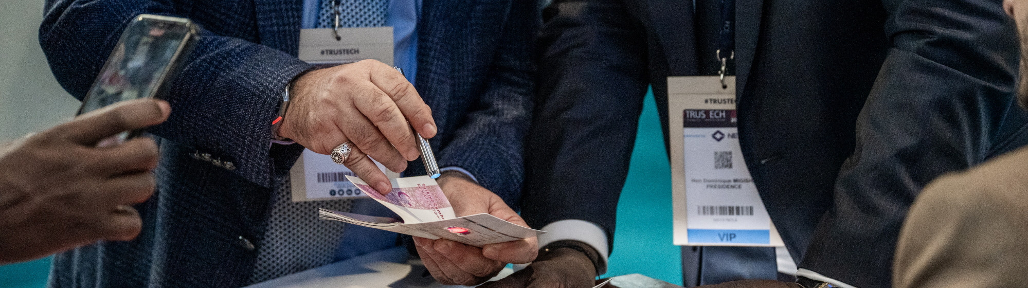 Exposant montrant à des visiteurs la sécurité d'un passeport sur son stand à TRUSTECH