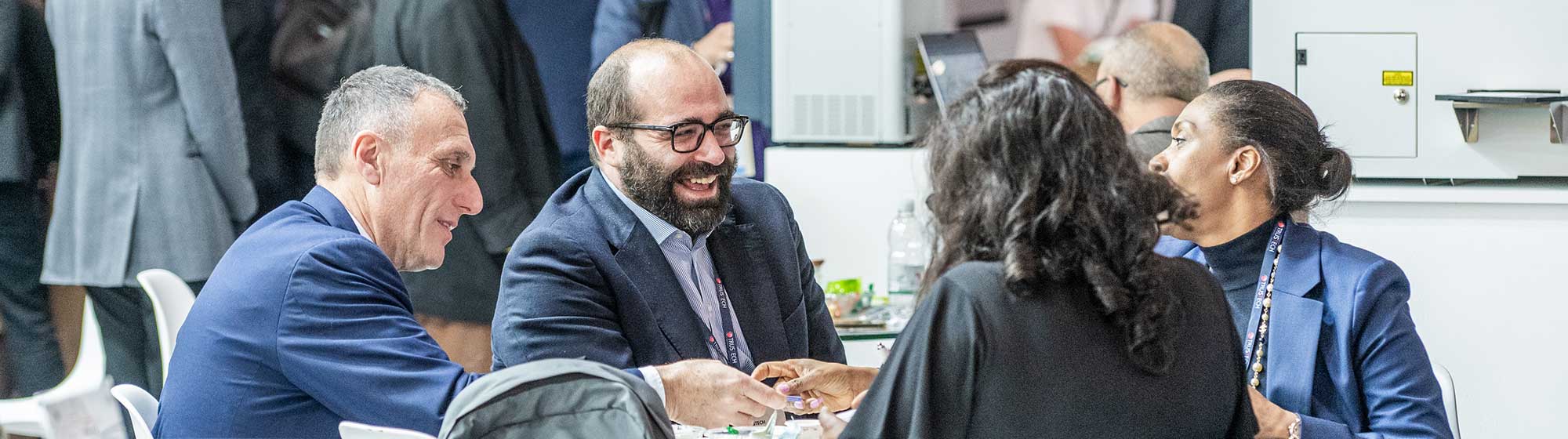 Four exhibitors chat smilingly around a table on a stand