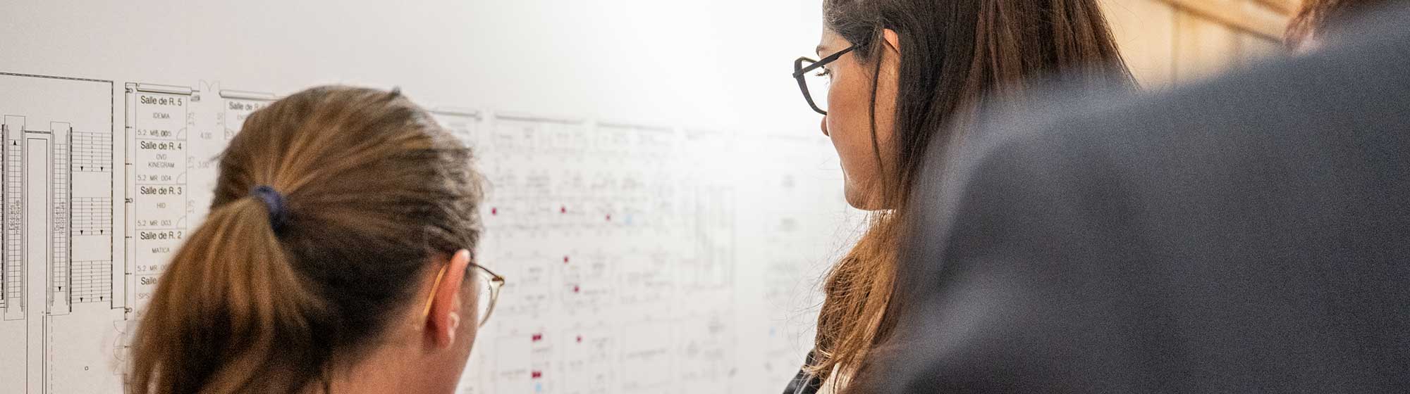 Two people looking and pointing to the exhibition floor plan during the TRUSTECH event as part of the 2024 rebooking