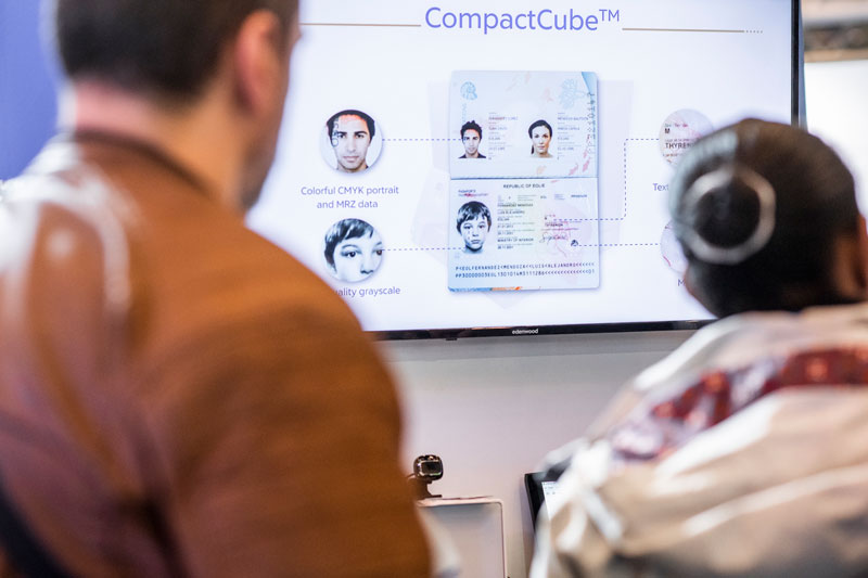 Two visitors watch a projection of a passport on a screen