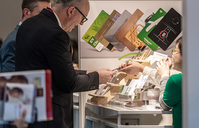 Visiteur qui consulte des cartes de crédit personnalisées sur le stand d'un exposant à TRUSTECH