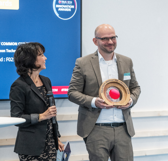 Un lauréat des TRUSTECH Innovation Awards sur scène avec le trophée entre les mains.